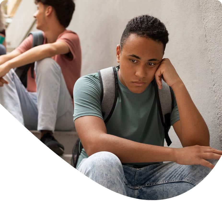 Jongere met backpack zit verdrietig op straat.